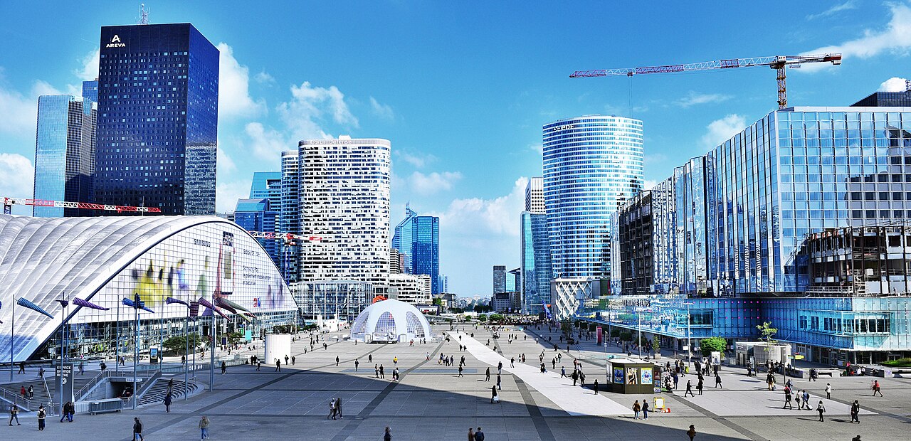 Le parvis de La Défense entouré du CNIT et de ses tours, sous un ciel bleu.
